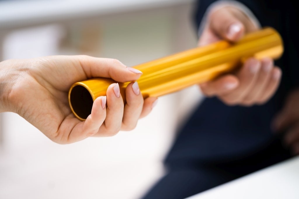 Close-up of two people passing a golden baton symbolising Baton Advisory’s trusted business ownership transition services