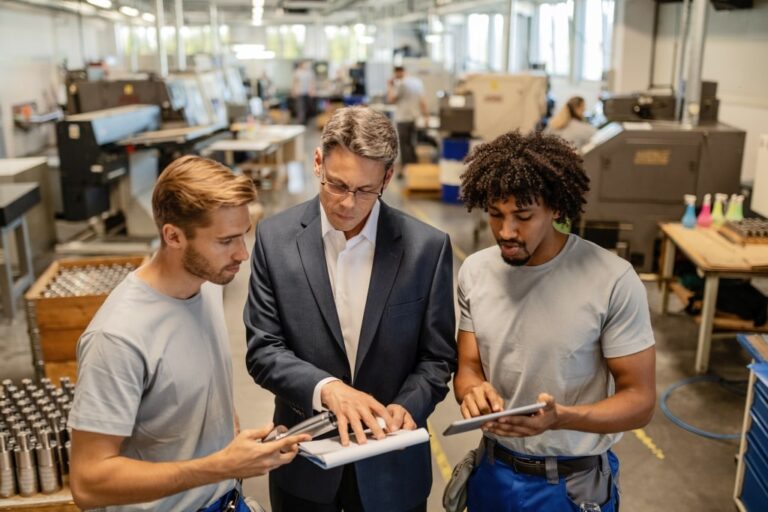 Baton Advisory manager reviewing documents with two factory workers to prepare a business for sale